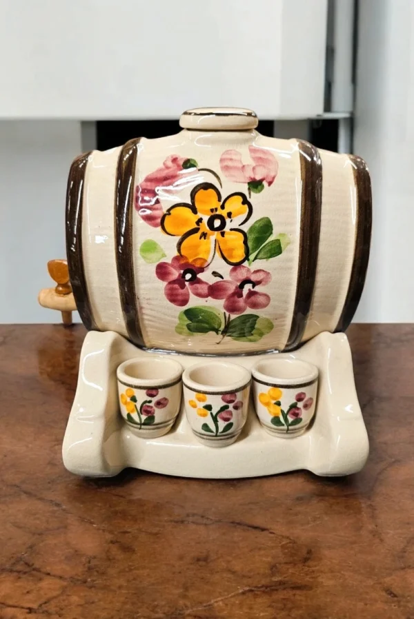Ceramiczna beczułka z kranikiem na drewnianej podstawce – naczynie do serwowania trunków.