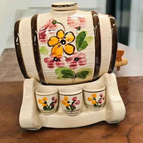 Ceramiczna beczułka z kranikiem na drewnianej podstawce – naczynie do serwowania trunków.