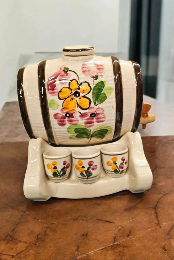 Ceramiczna beczułka z kranikiem na drewnianej podstawce – naczynie do serwowania trunków.
