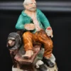 Ręcznie malowana figurka – starszy mężczyzna na ławce z butelką – ceramika, wys. 20 cm