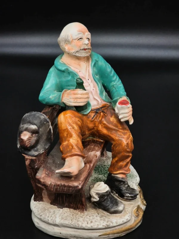 Ręcznie malowana figurka – starszy mężczyzna na ławce z butelką – ceramika, wys. 20 cm
