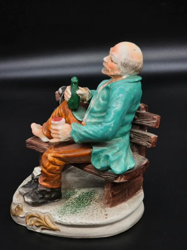 Ręcznie malowana figurka – starszy mężczyzna na ławce z butelką – ceramika, wys. 20 cm
