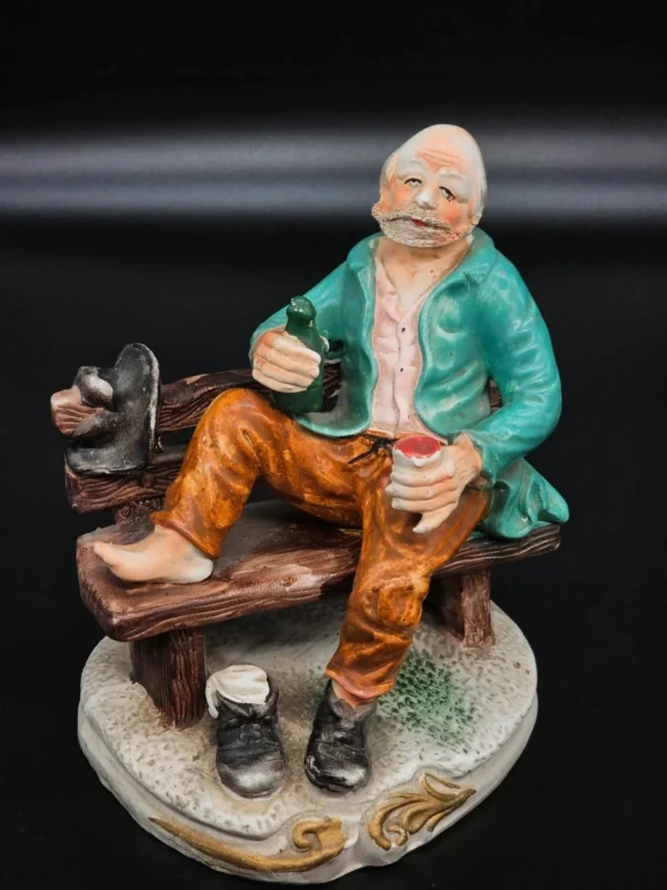 Ręcznie malowana figurka – starszy mężczyzna na ławce z butelką – ceramika, wys. 20 cm
