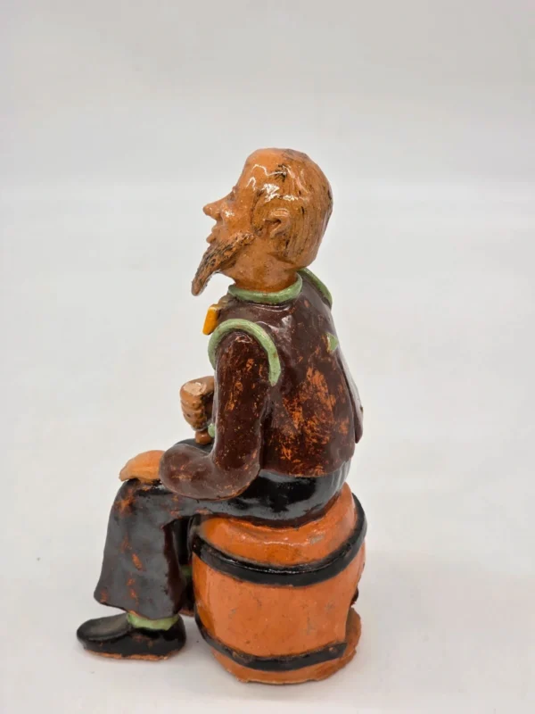 Figurka ceramiczna starszy pan siedzący na beczce wysokość 22 cm