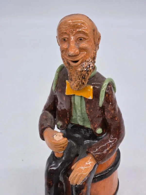 Figurka ceramiczna starszy pan siedzący na beczce wysokość 22 cm