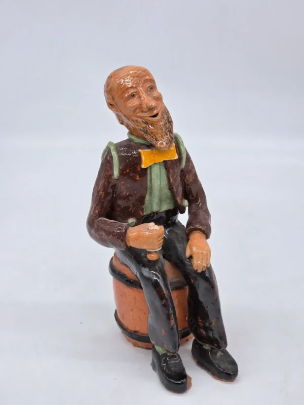Figurka ceramiczna starszy pan siedzący na beczce wysokość 22 cm