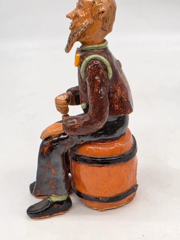 Figurka ceramiczna starszy pan siedzący na beczce wysokość 22 cm